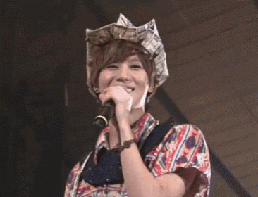 a woman singing into a microphone wearing a hat