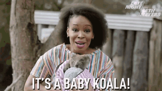 a woman is holding a baby koala in her arms and says `` it 's a baby koala ! ''