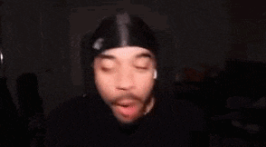 a blurry picture of a man wearing a bandana and a hat .