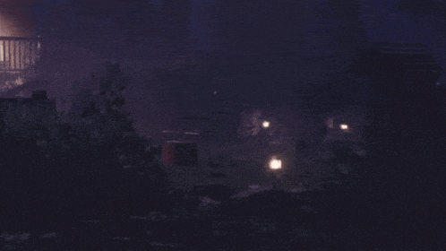 a dark night scene with a few lights in the distance