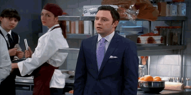 a man in a suit and tie stands in front of a shelf that says super
