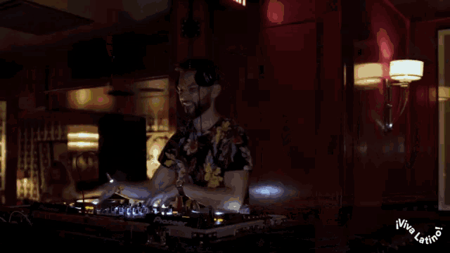 a man is playing music in front of a wall with a picture of the queen on it
