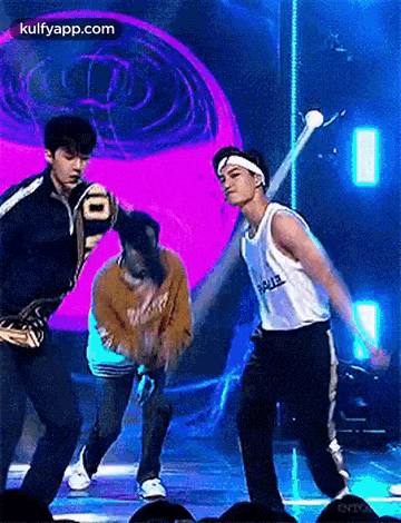 a group of young men are dancing on a stage in front of a purple background .