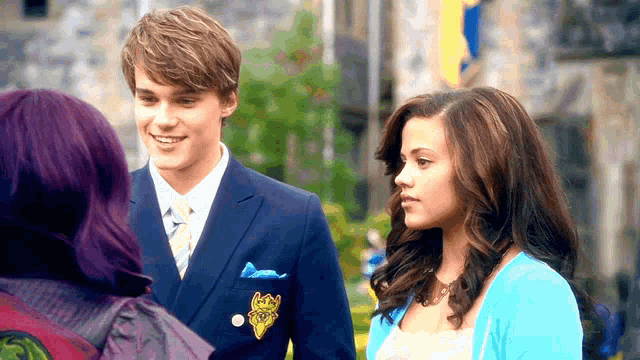 a man and a woman are standing next to each other and the man is wearing a blue suit and tie