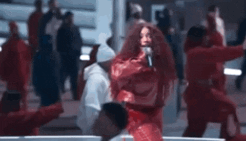 a woman with red hair is singing into a microphone in front of a crowd .
