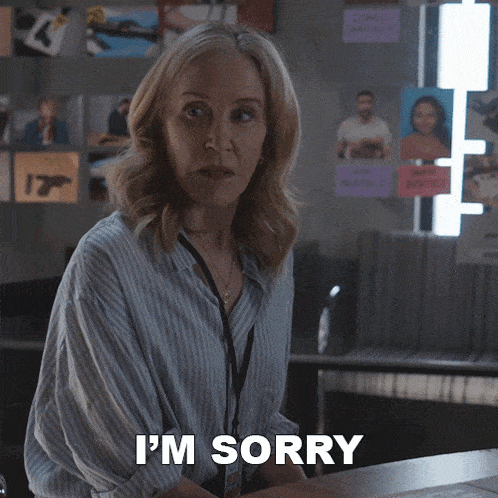 a woman says i 'm sorry while standing in front of a desk