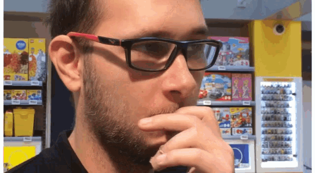 a man wearing glasses and a black shirt in front of a lego store
