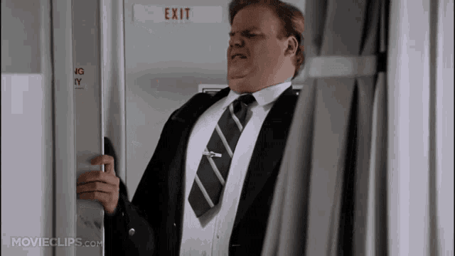 a man in a suit and tie opens an exit door