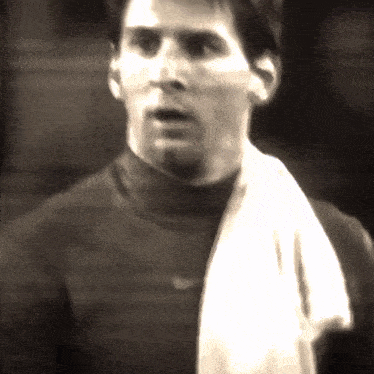 a man with a towel around his neck is wearing a black turtleneck