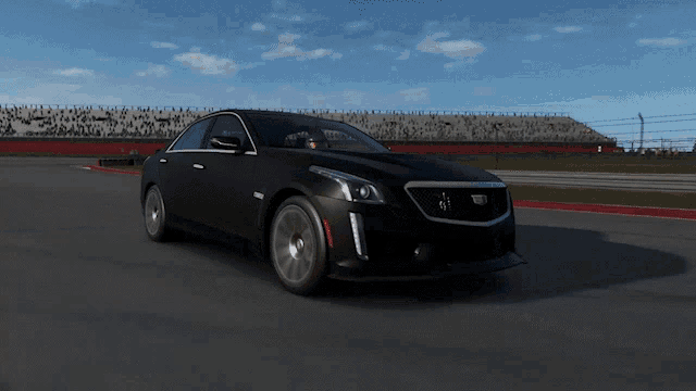 a black cadillac is driving down a track