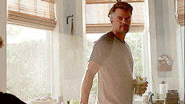 a man standing in front of a window holding a glass