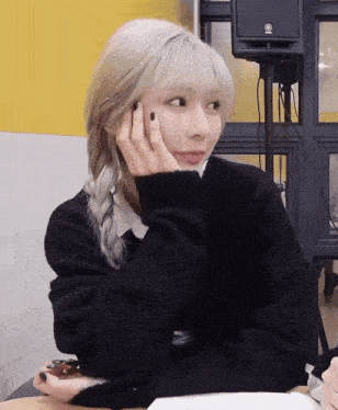 a woman wearing a black sweater has a yamaha speaker behind her