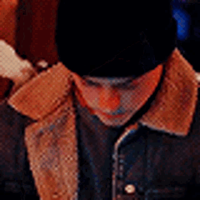a man wearing a fur collared jacket and a black hat is looking down .
