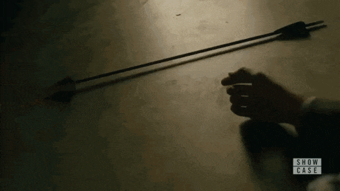 a person is holding a broken arrow in their hand on a table .