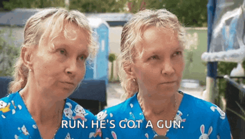 two women in blue scrubs are standing next to each other and one of them is saying run he 's got a gun
