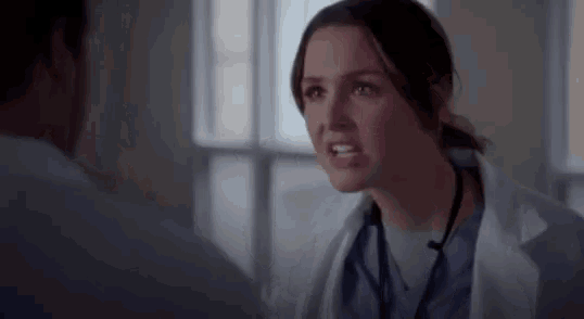 a woman in a lab coat is talking to a man in a hospital .