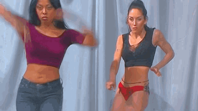 two women are dancing in front of a curtain .