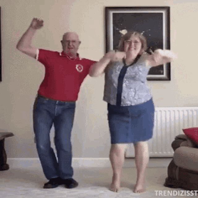 an elderly couple is dancing together in a living room .