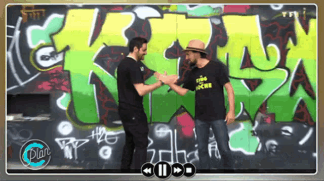 two men shaking hands in front of a wall with graffiti that says " rire joche "