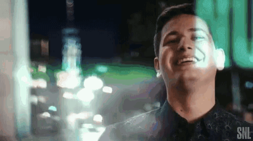 a man is laughing in front of a window with a sign that says snl on it .