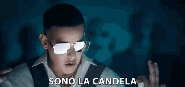 a man wearing sunglasses and a ring says sono la candela .