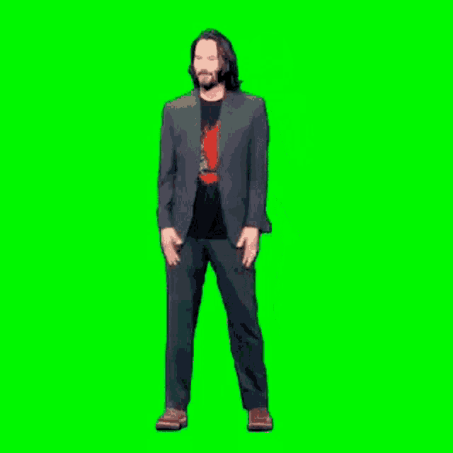 keanu reeves is standing in front of a green screen wearing a suit and a black shirt .