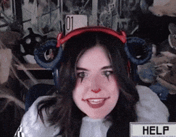 a woman wearing headphones and a clown makeup smiles in front of a help button