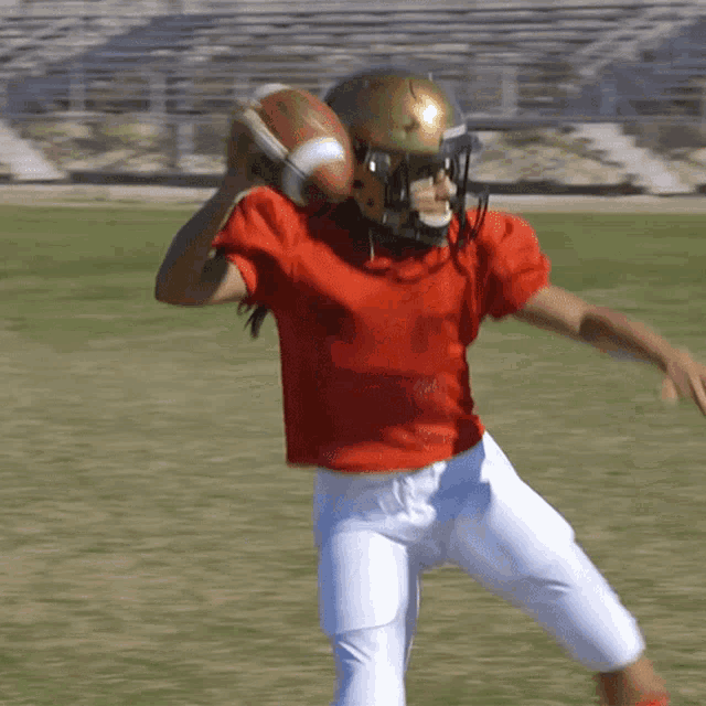 a football player wearing a red shirt and white shorts is throwing a football