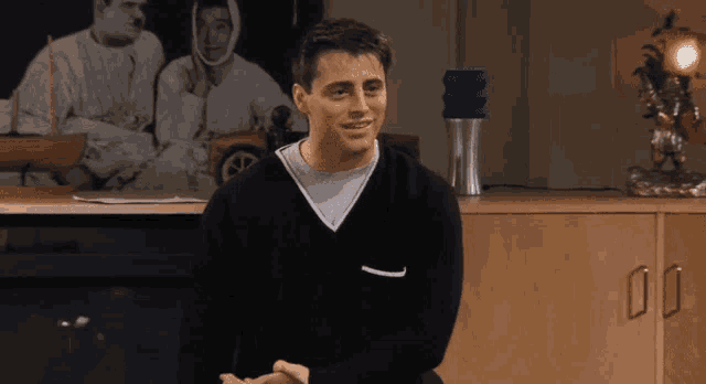a man in a black sweater is sitting in front of a picture of a man in a wheelchair