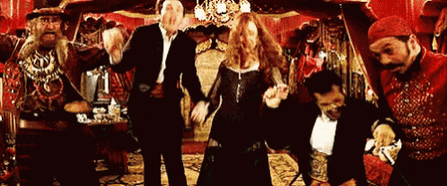 a group of people are dancing in a room with red curtain