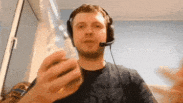 a man wearing headphones and a microphone holds a bottle