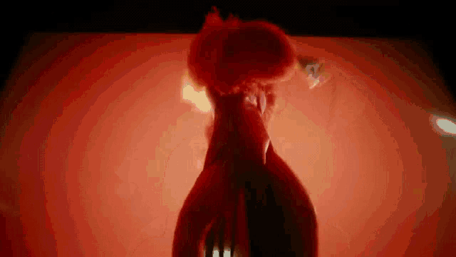 a woman in a red dress is standing in front of a red wall .