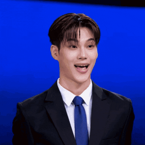 a man in a suit and tie is smiling with a blue background