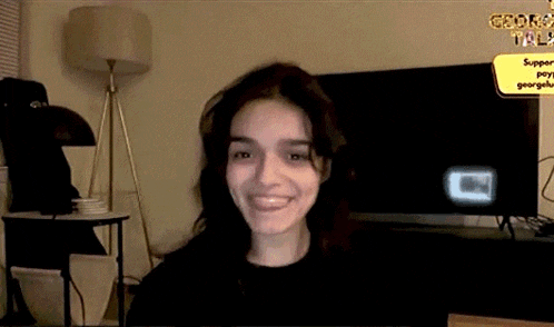 a woman is sitting in front of a television in a living room and smiling .