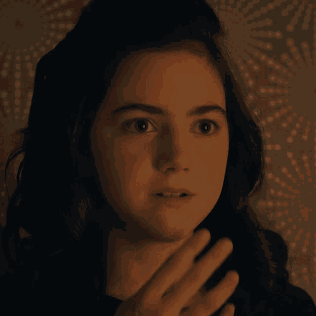 a young girl covering her mouth with her hand and looking surprised