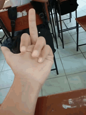 a person 's hand is shown in front of a classroom with the number 28 written on a desk