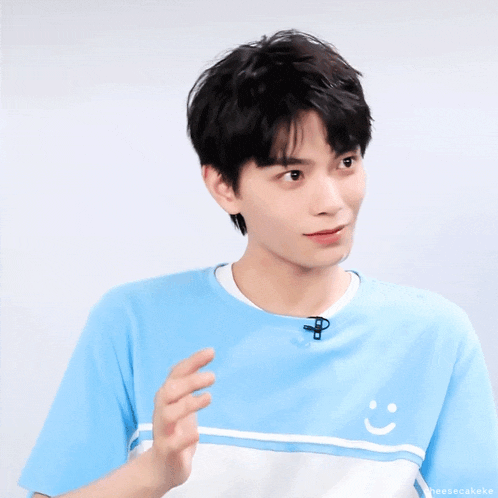 a man wearing a blue shirt with a smiley face on the front