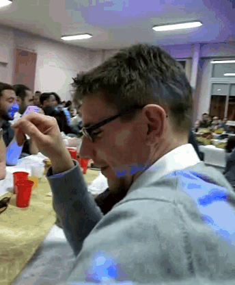a man wearing glasses sits at a table with red cups on it