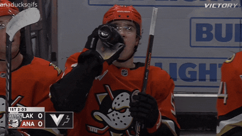 a hockey player drinks from a bottle in front of a bud light banner
