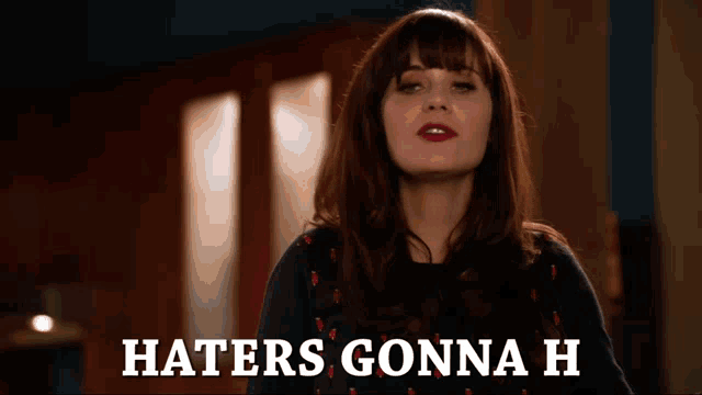 a woman says haters gonna h while standing in front of a window