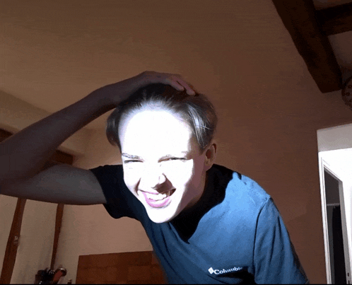 a man wearing a blue columbia shirt is making a face