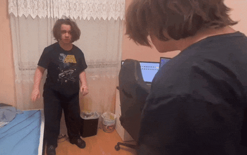a man wearing a star wars shirt stands in a room