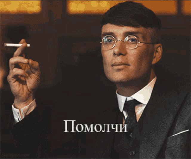 a man in a suit and tie smoking a cigarette with the word pomolchi on the bottom right