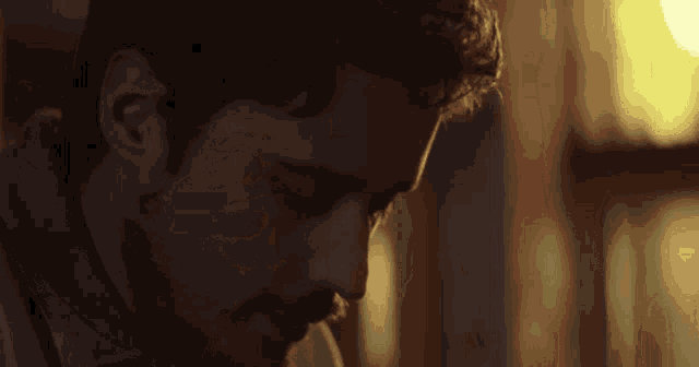 a man with a beard and a blue shirt is looking down