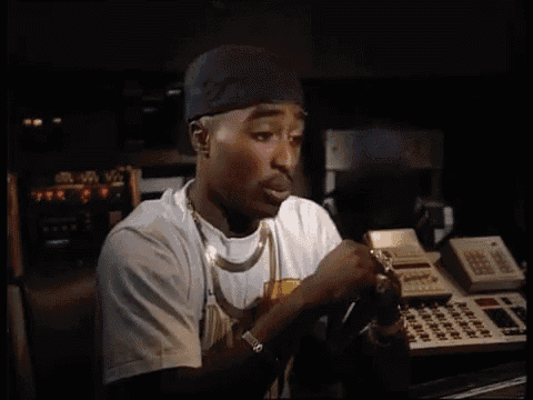 a man wearing a black hat and a white shirt is sitting in front of a calculator