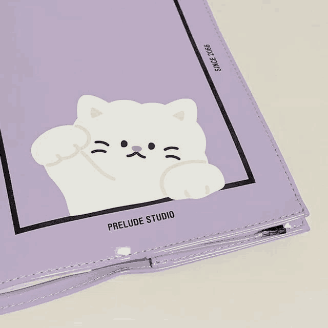 a purple notebook with a white cat on it and prelude studio written on it