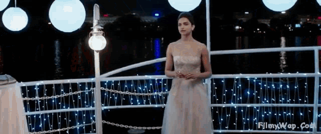 a woman in a white dress is standing on a boat with christmas lights .