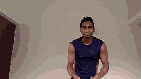 a man in a blue shirt is standing in front of a white wall .