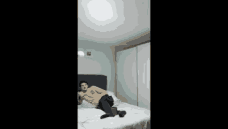 a man is laying on a bed in a bedroom with a picture on the wall .