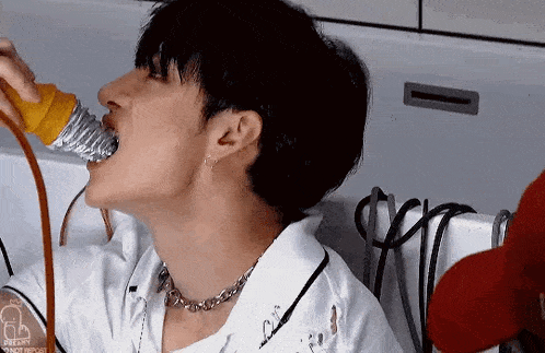 a man is drinking water from a plastic bottle .